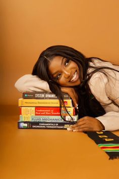 a smiling woman leaning on a stack of books