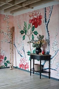 a room with flowers painted on the wall and wooden flooring in front of it