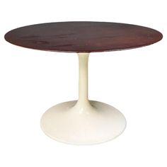 an oval wooden table with white base on a white background in the shape of a tulip