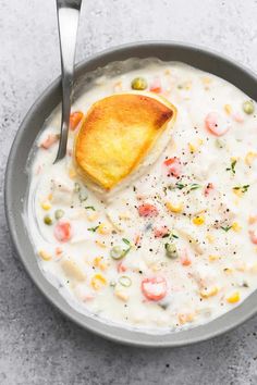 a bowl of soup with a spoon in it and a piece of bread on the side