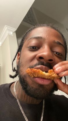 a man with dreadlocks is taking a bite out of some food while wearing a black t - shirt