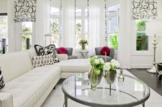 a living room filled with white furniture and lots of window sill space in front of the couches