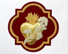 a red and gold heart shaped brooch with leaves on it's back side