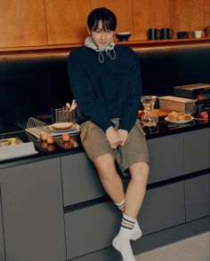 a woman sitting on top of a kitchen counter