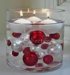 two candles are sitting in a glass bowl filled with ornaments