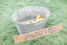 a wooden sign that says hook a duck next to a bucket with two rubber ducks in it