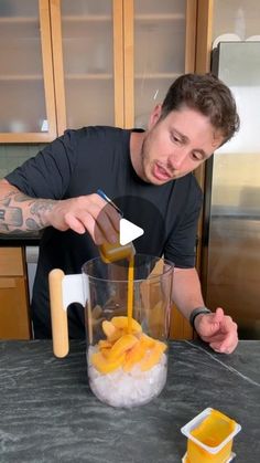 a man is making something in a blender with oranges and ice cubes