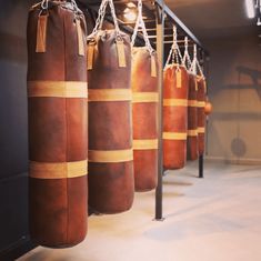 there are many brown boxing bags hanging from the wall