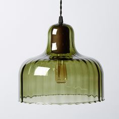 a green glass pendant light hanging from a ceiling fixture with measurements in front of it