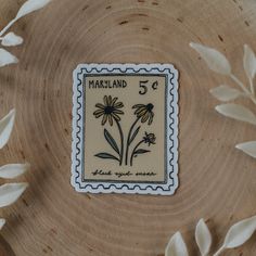 a stamp with flowers on it sitting on top of a wooden table next to leaves