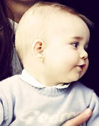 a woman holding a baby who is wearing a blue sweater and white collared shirt