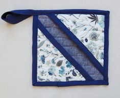 a blue and white patchwork piece with a ribbon hanging from it's side