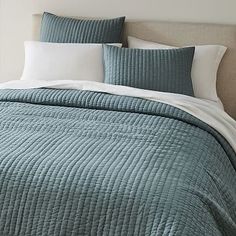 a bed with blue and white bedspread in a bedroom next to a window