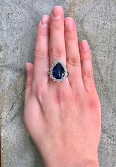 a woman's hand with a blue stone ring on top of her left hand