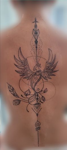 the back of a woman's shoulder with an arrow and bird tattoo on it