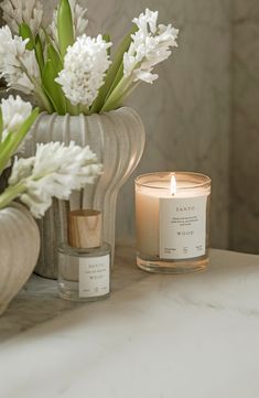 a candle sitting on top of a counter next to some white flowers and vases