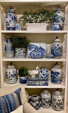 a blue and white china cabinet filled with vases, pots and other decorative items