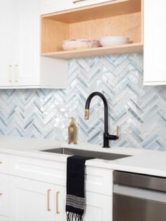 a kitchen with white cabinets and marble backsplash, black faucet sink