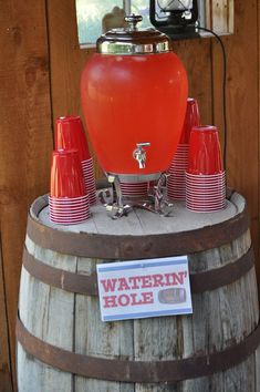 a barrel with red cups and a waterin hole sign on the top that says,