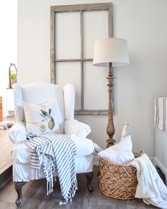 a white chair sitting in a living room next to a lamp