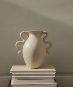 a white vase sitting on top of a stack of books