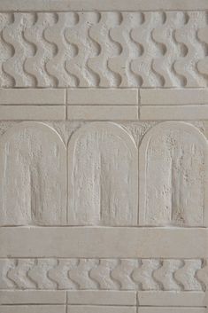 a close up of a white brick wall with decorative designs on the side and sides