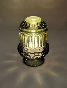 an ornate glass jar sitting on top of a gray tablecloth covered floor next to a black candle holder