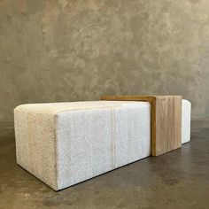 a white couch sitting on top of a floor next to a wooden block in front of a wall