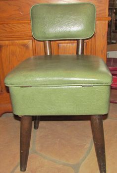 a green chair sitting on top of a floor next to a wooden dresser with drawers