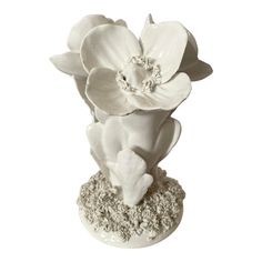 a white vase with flowers in it sitting on a rock base, against a white background