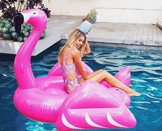 a woman sitting on an inflatable pink flamingo pool floatie next to a swimming pool