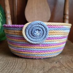 Yellow, pink, and purple rope bowl with a floret on a wooden chair Coiled Fabric Bowl, Coil Basket, Fabric Bowl, Rope Bowls, Coiled Fabric Basket, Rope Baskets, Coiled Baskets, Fabric Bowls, Fabric Basket