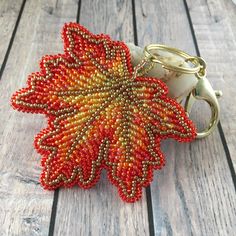 a beaded keychain with an orange flower on it sitting on a wooden surface