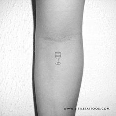 a black and white photo of a person's arm with a wine glass tattoo on it