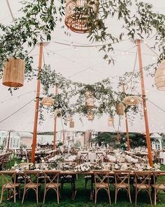 an outdoor tent set up with tables and chairs for a wedding or party under hanging lights