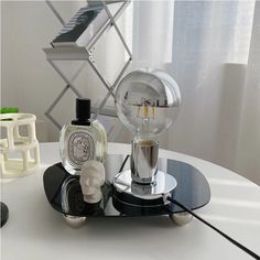 a white table with some bottles on it and a lamp in the middle, sitting on top of a black tray