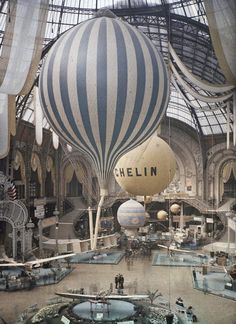 two hot air balloons are suspended from the ceiling in an indoor shopping mall with people looking at them