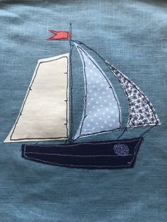 an embroidered sailboat is shown on the blue fabric