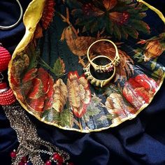 two gold rings sitting on top of a flowered tray next to other jewelry items