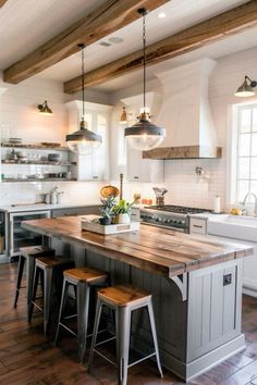 a kitchen island with stools in front of it and lights hanging from the ceiling