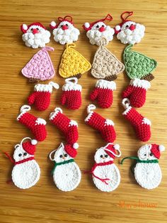 crocheted christmas ornaments are arranged on a wooden surface, including santa's stockings and snowmen