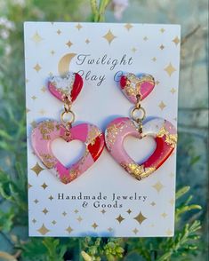 pink and red heart shaped earrings with gold sparkles on them, hanging from a card