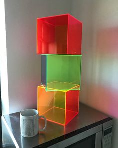 a microwave oven sitting on top of a counter next to a coffee cup and mug