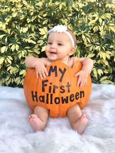 a baby sitting on top of a fake pumpkin