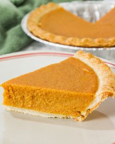 a slice of pumpkin pie sitting on top of a white plate next to another pie