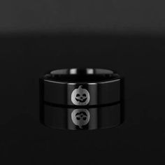 a black ring with two smiley faces on the side and one in the middle, against a black background