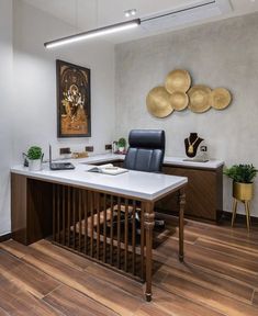 an office with wood flooring and white counter tops, along with two paintings on the wall