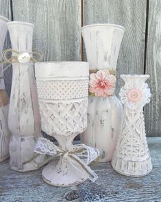 several white vases with flowers and bows are sitting on a wooden table next to each other