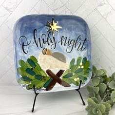 a ceramic plate with a nativity scene painted on it and a succulent plant next to it