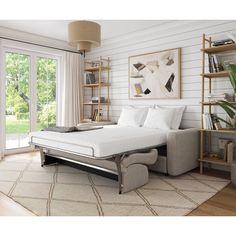 a white bed sitting on top of a wooden floor next to a book shelf filled with books